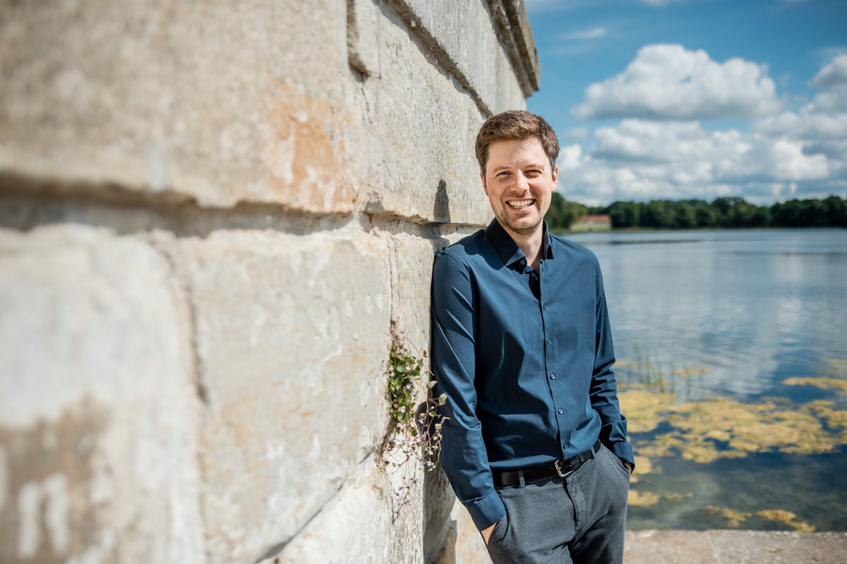 Dr. Christopher Schwake an einer Mauer am Wasser
